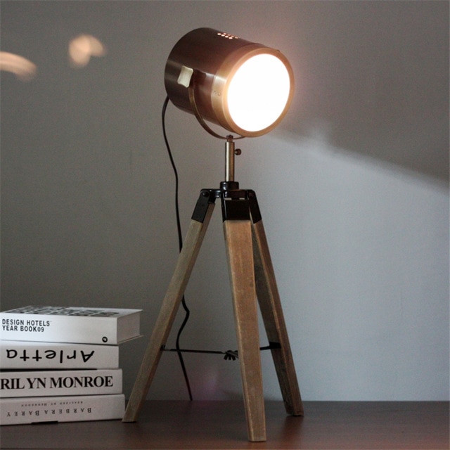 Lampe projecteur design vintage et rétro en métal style cuivre et trépied en bois.